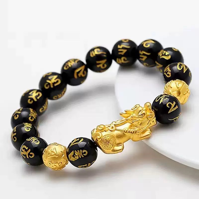 Gold-tone Pixiu charm on a black beaded bracelet with gold script