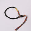Black obsidian beaded bracelet with a colorful tassel resting on a white plate