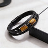 Close up of a black braided leather bracelet with two tiger eye stones.
