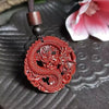 Close-up of a red circular dragon pendant on a dark cord