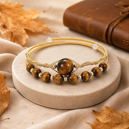 Gold tone adjustable cuff bracelet with brown natural stone beads on a stone display stand