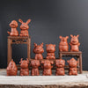 A group of small brown clay figurines shaped like the twelve Chinese zodiac animals sitting on a wooden surface.