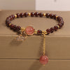 Close-up of a red garnet beaded bracelet with a butterfly charm on a wooden surface