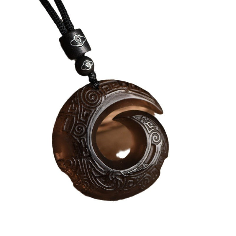 Close up of a carved natural black obsidian pendant on a black cord