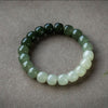 Two gradient green and white jade bracelets on a textured surface