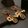 Close-up of a brass keychain with a spinning horse zodiac coin and gourd charm