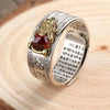 Close up of a vintage style adjustable ring with a red Pixiu charm and engraved text on the band