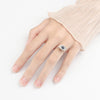 Close-up of a hand wearing a silver-tone ring with a blue evil eye center that can rotate.