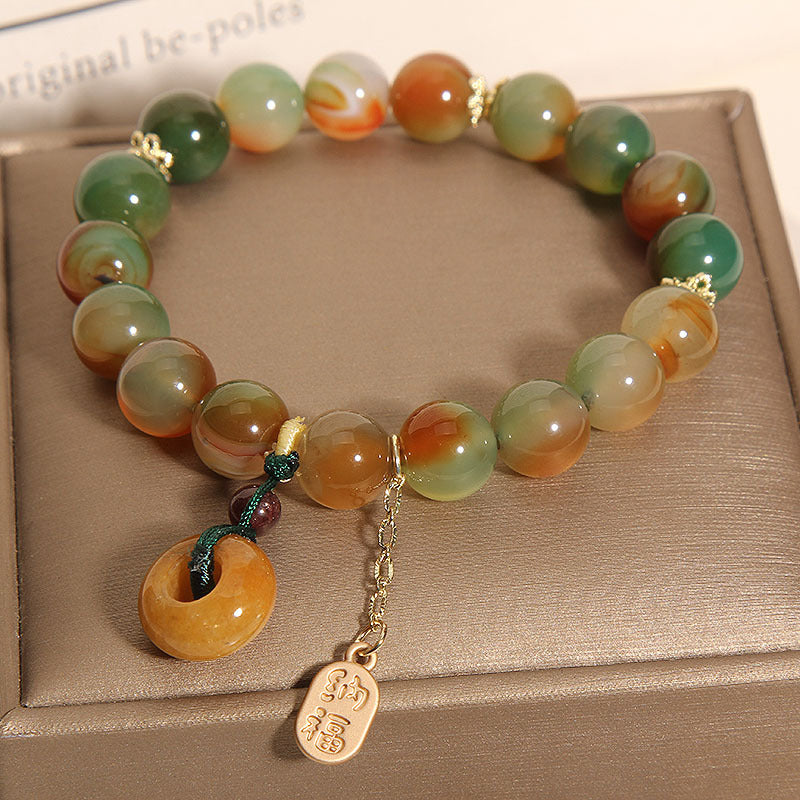 Close-up of a colorful agate beaded bracelet with a donut-shaped charm and gold tag