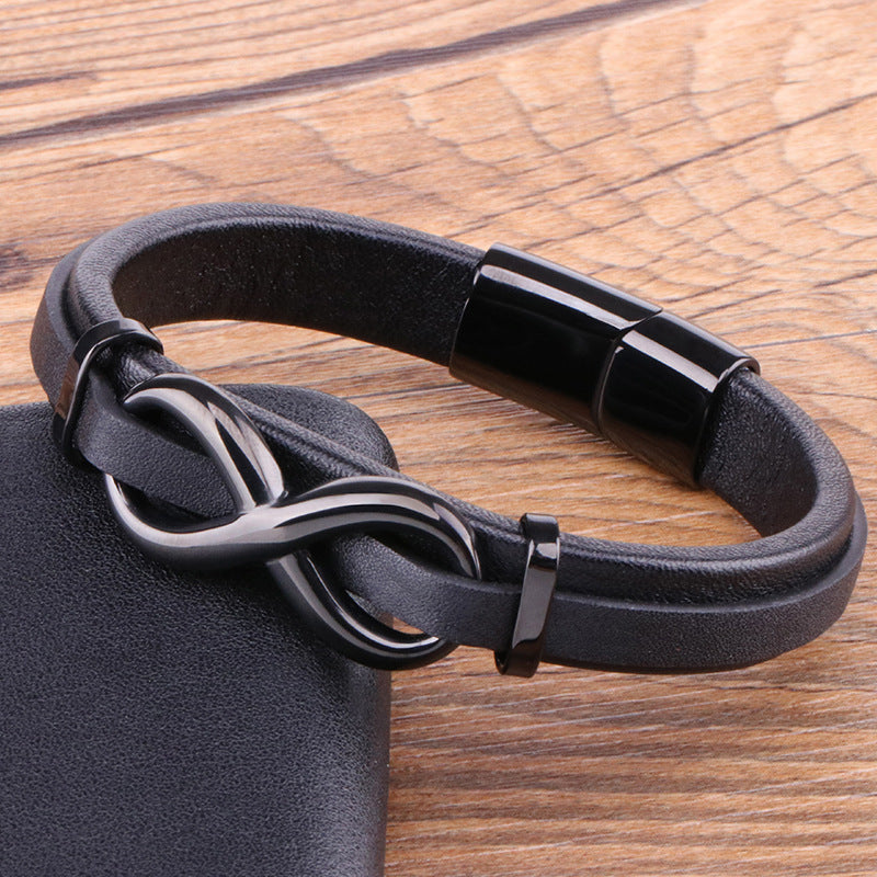 Black leather bracelet with a dark metal infinity symbol clasp on a wooden surface