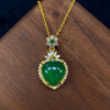 Green heart-shaped chalcedony pendant on a gold-tone chain resting on wood