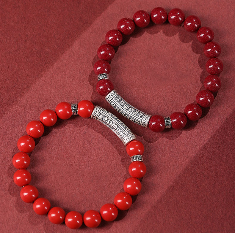 Red cinnabar bead bracelet with a silver cylinder charm engraved with mantras