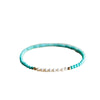 Close up of a thin turquoise and pearl beaded bracelet on a woman's wrist