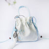 Light blue and white embroidered bucket bag with tassel hanging from drawstring