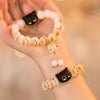 Hand holding a white bodhi seed bracelet with a black cat head charm and dangling paw beads