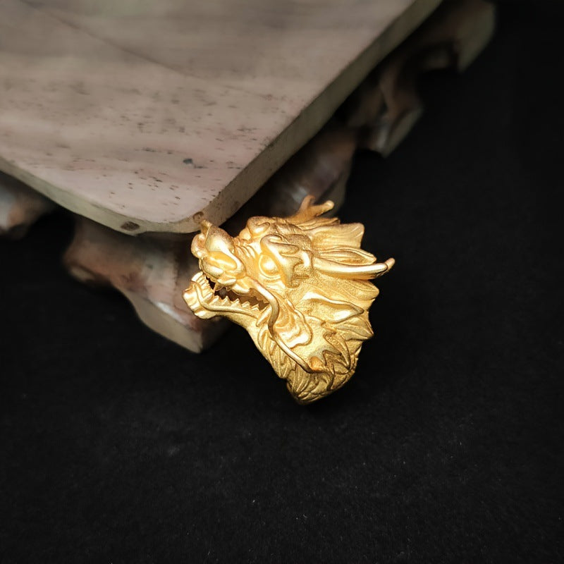 Close-up view of a gold-tone alloy ring shaped like a dragon head on a wooden stand