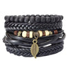 A stack of black faux leather bracelets with beads and a gold-tone leaf charm on a wrist.