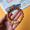 Hand holding a bracelet made of polished brown and tan barrel-shaped bodhi seed beads