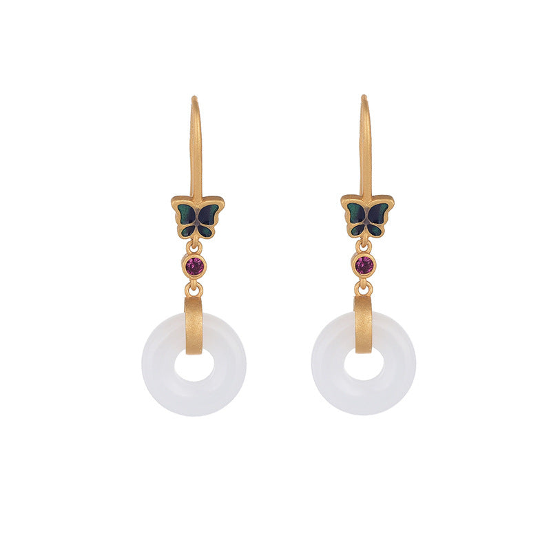 Gold-tone earrings with a blue butterfly and a white faux jade ring hanging from a display stand.