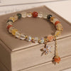 Single loop bracelet with mixed color rutilated quartz beads and a gold-tone butterfly charm with clear stones.