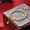 Light green 6mm jade bead bracelet with gold gourd charm on grey box