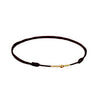 Black braided cord bracelet with a central gold heart-shaped bead on a white background