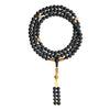 Black medicinal amber mala bracelet wrapped around a wrist with gold accents and a tassel