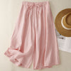 Pink wide leg linen pants with elastic waistband lying flat on a beige surface