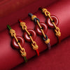 Four braided rope bracelets with red cinnabar donut charms and gold knots on a red background