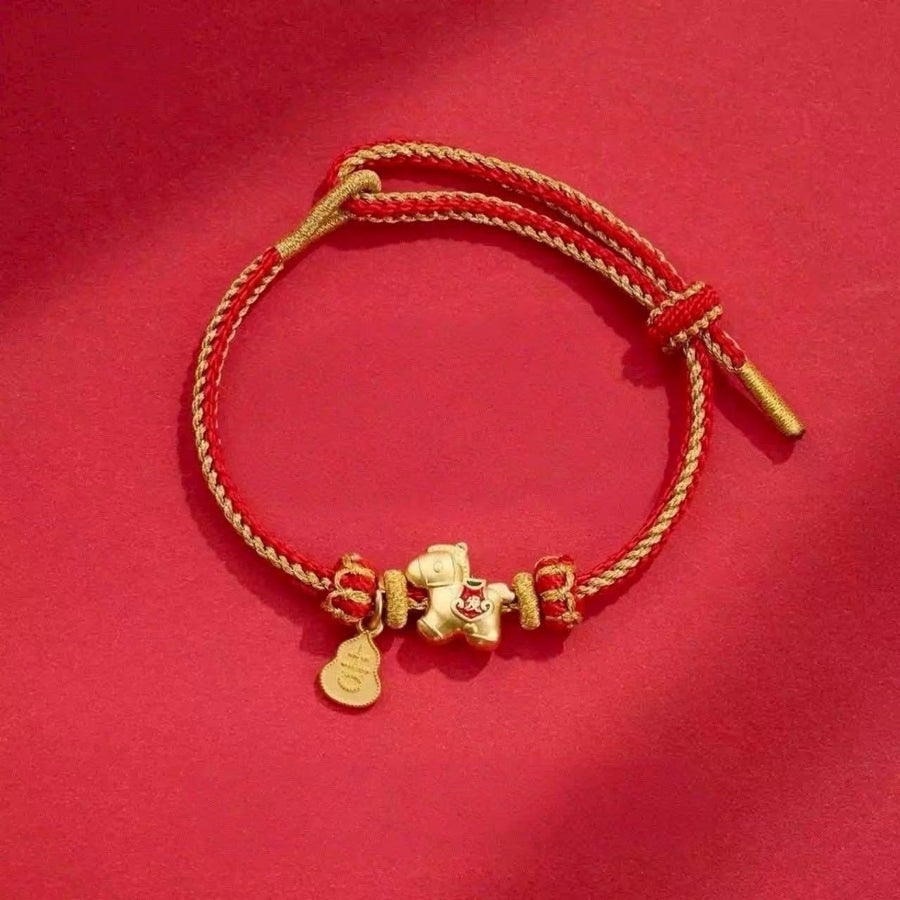 Red braided cord bracelet with gold-tone horse charm on red background