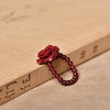 Close up of a red cinnabar rose bead ring resting on a wooden block