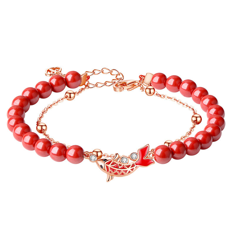 Close up of a sterling silver bracelet with red beads and a koi fish charm on a wrist