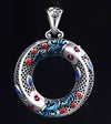 Close up of a copper koi fish peace buckle pendant with blue and red enamel details on a black cord