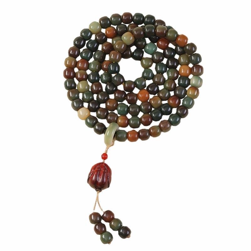 Coiled wooden mala bracelet with 108 beads and a tassel on a neutral background