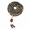 Coiled wooden mala bracelet with 108 beads and a tassel on a neutral background