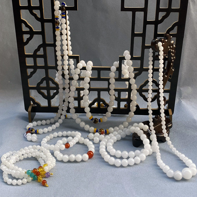 White golden jade beads arranged as bracelets and malas on a display stand