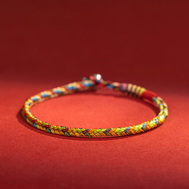 Close up view of a multicolored hand braided cord bracelet on a red background