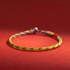 Close up view of a multicolored hand braided cord bracelet on a red background