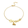 Gold tone anklet with five coin charms and two small bells worn on an ankle