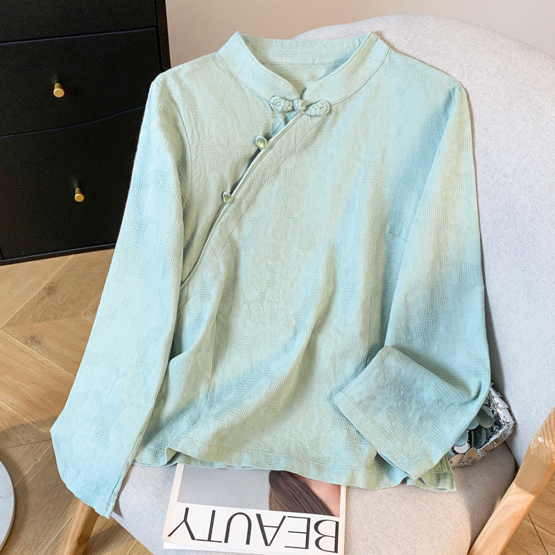 Light blue long sleeve shirt with mandarin collar and frog buttons laid on a chair