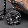 Close up of a carved black obsidian pendant featuring a dragon and pixiu design on a peace buckle shape