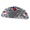 Close up of a silver tone metal hair comb with red and blue stones and a bird design
