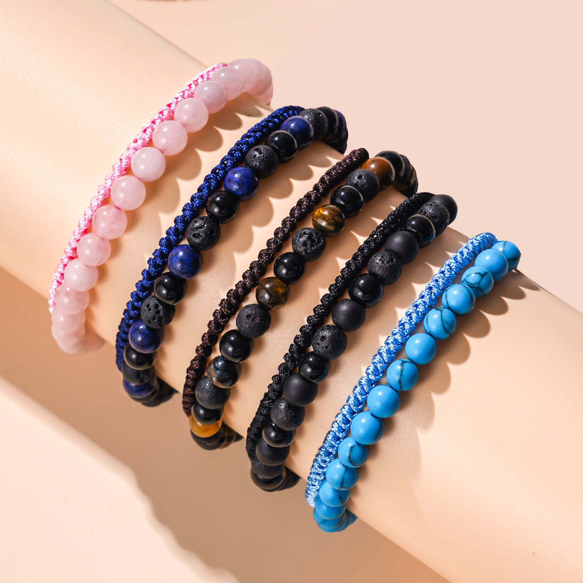 A set of five colorful beaded bracelets with braided cords worn on a wrist