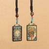 Two handmade ebony wood pendants with Tibetan thangka art hanging from dark cords