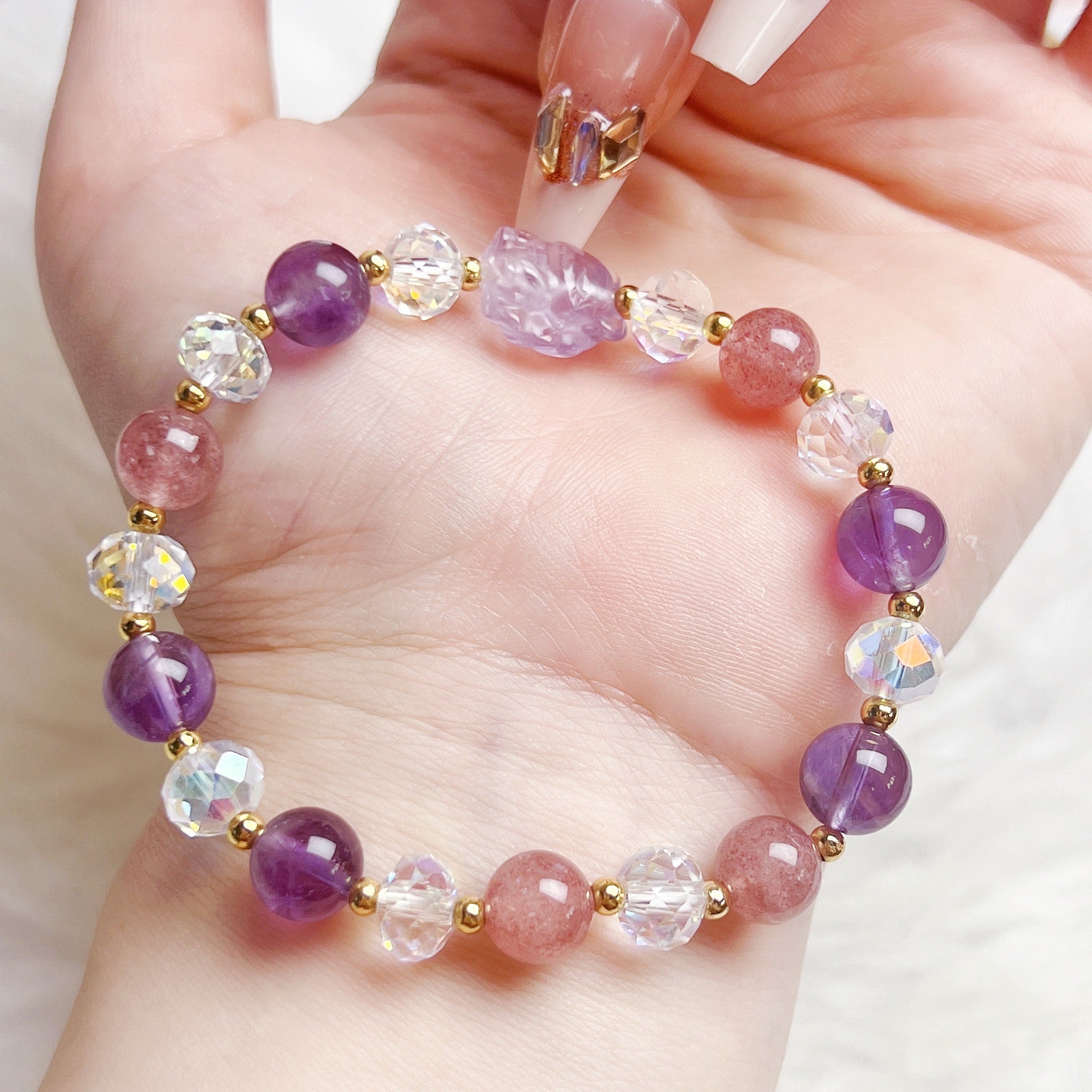 Close up of handmade bracelet with purple and pink crystal beads and a carved fox charm on a wrist