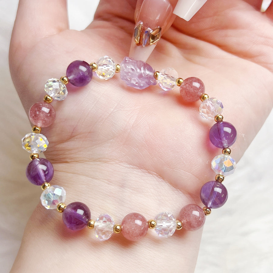 Close up of handmade bracelet with purple and pink crystal beads and a carved fox charm on a wrist