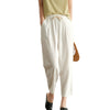 Model wearing white cotton harem pants with hands in pockets