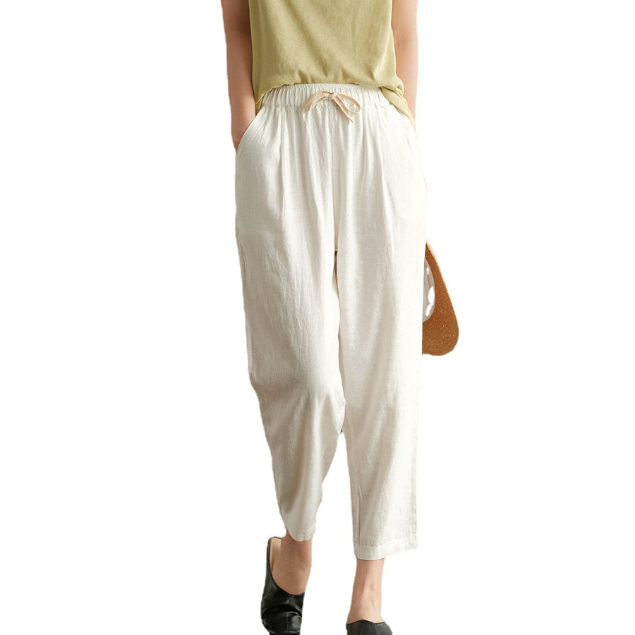 Model wearing white cotton harem pants with hands in pockets