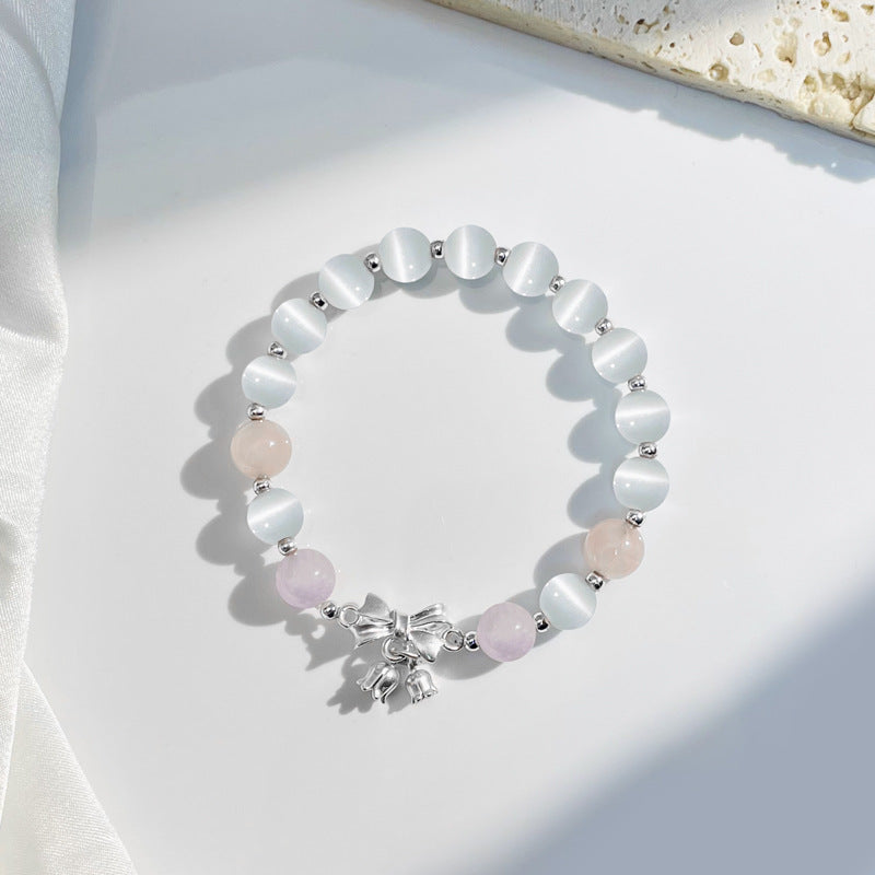 Lavender cat's eye bead bracelet with a silver bow charm on a white background
