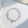 Lavender cat's eye bead bracelet with a silver bow charm on a white background